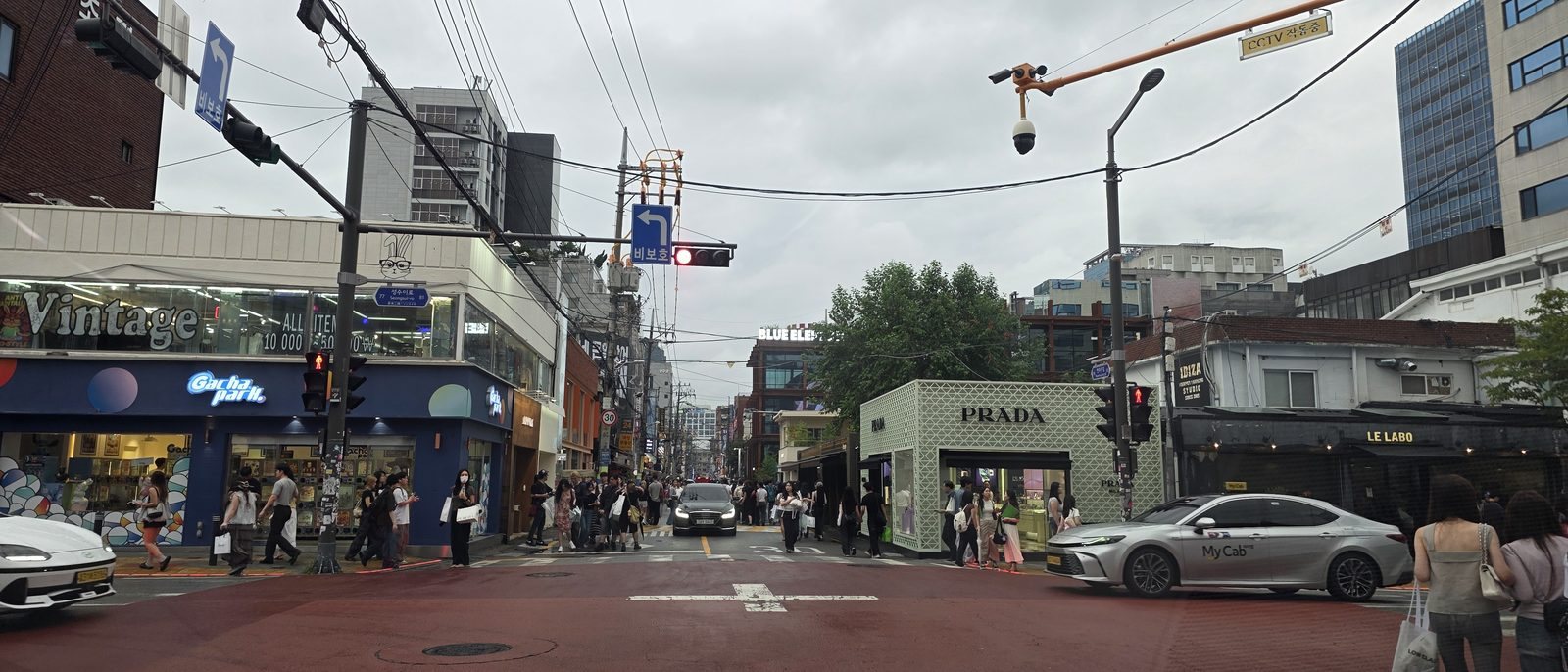 성수이로 사거리 전경, 왼쪽에 만원 균일가 빈티지 매장과 인형뽑기 가게, 오른쪽에 프라다 임시 구조물 매장이 마주 보고 있다