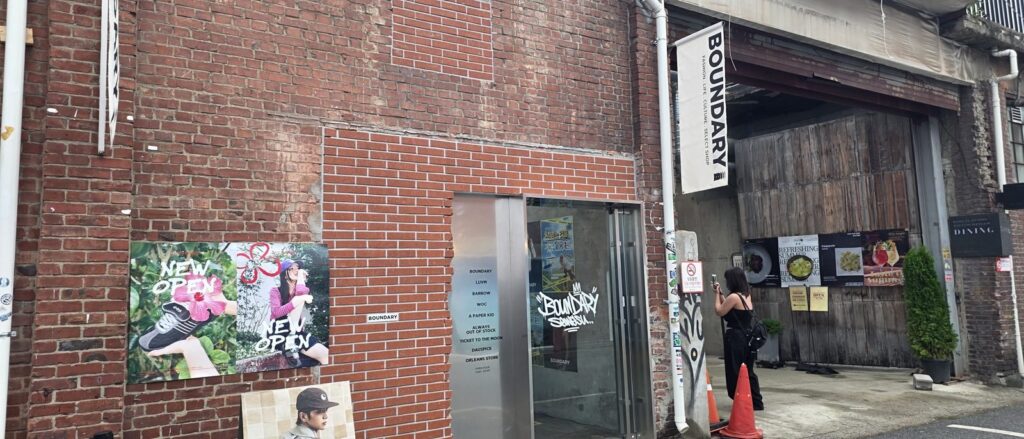 성수동 셀렉트숍 BOUNDARY 외벽, 오래된 벽돌과 새로 메운 벽돌의 색 차이가 드러나고 NEW OPEN 포스터가 붙어 있다