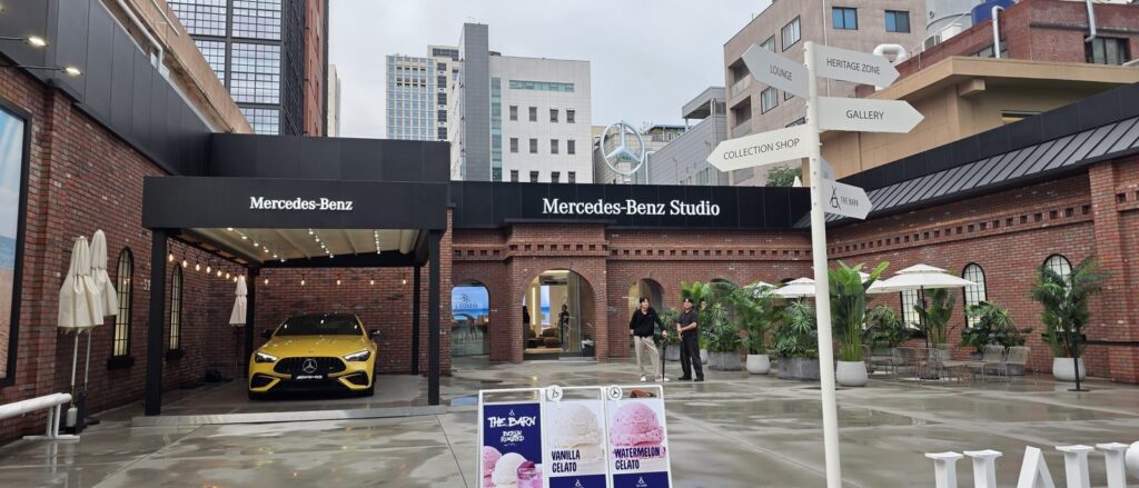 성수동 메르세데스벤츠 스튜디오, 벽돌 창고 외형을 유지한 건물 앞에 HERITAGE ZONE 표지판과 노란색 AMG 차량